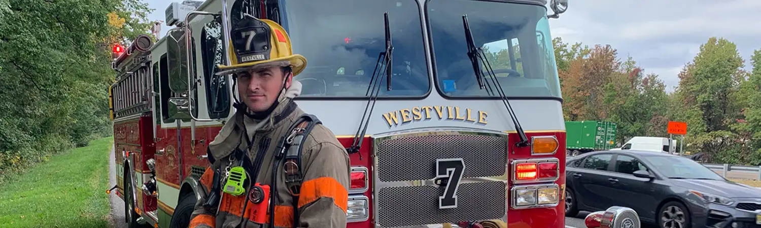 Firefighter standing in front of an engine during the day