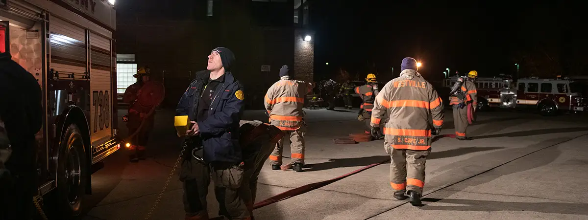 Firefighters in parking lot at night.
